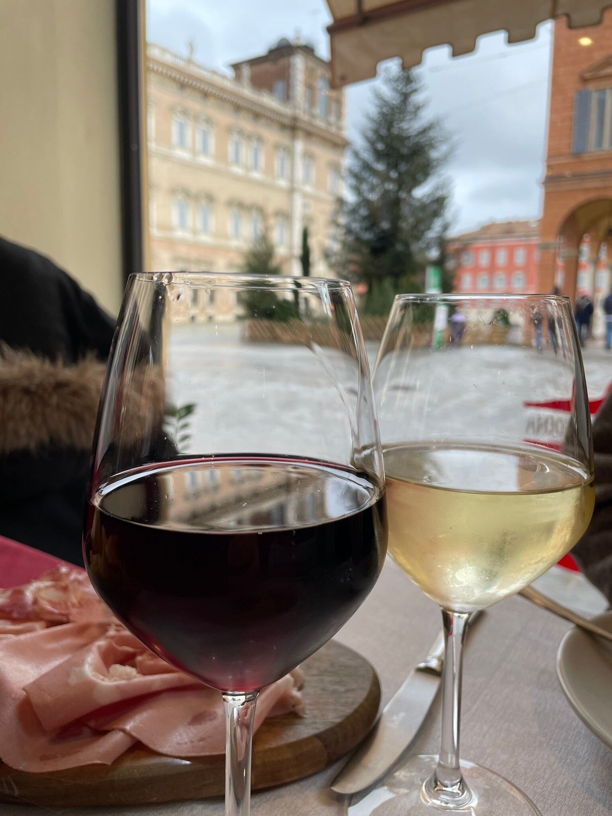 Due calici di vino sul tavolo con il Palazzo Ducale di Modena alle spalle