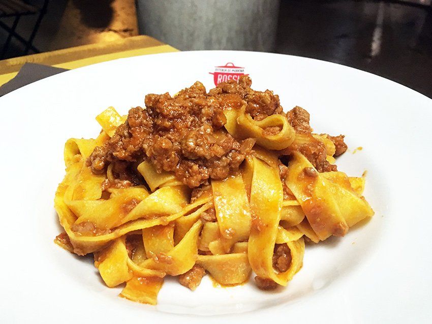 Tagliatelle al ragù nel piatto con il marchio della casa