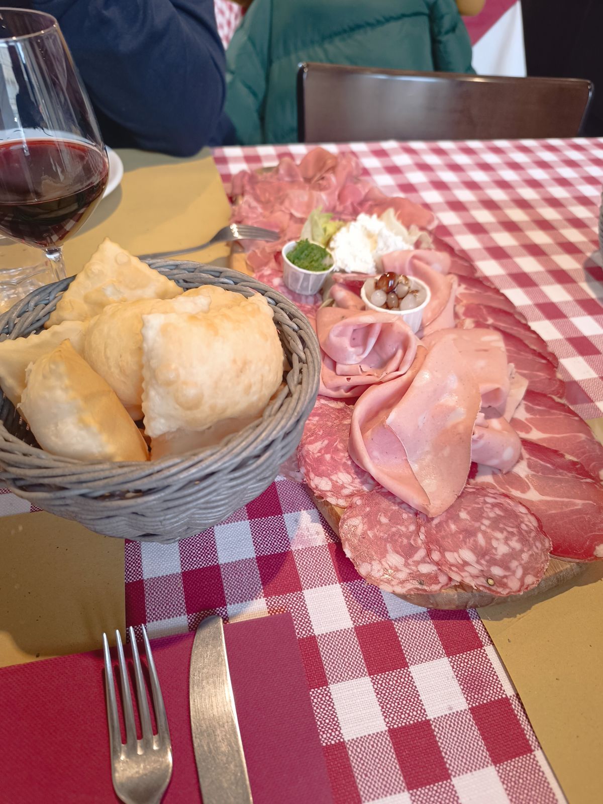 Tagliere di salumi e cestino di gnocco fritto sulla tovaglia a quadretti